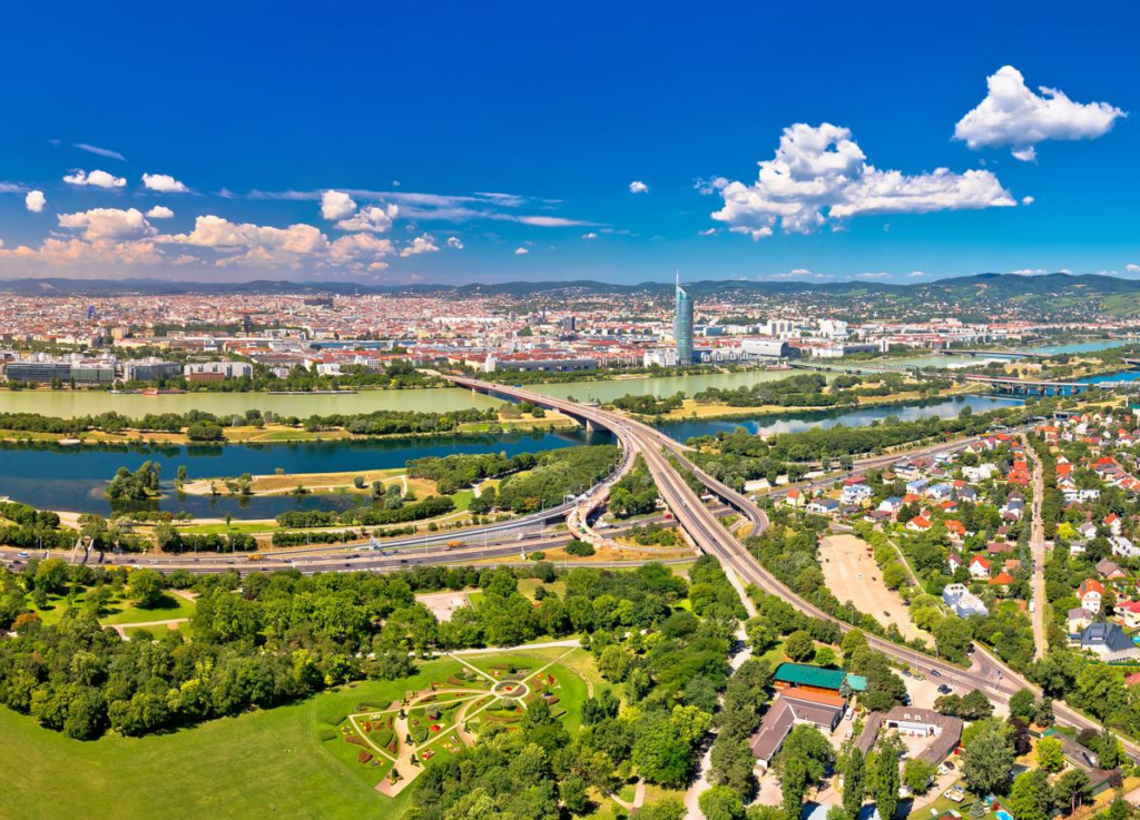 An aerial view of Austria featuring the Alps, Vienna cityscape, and the Danube River.