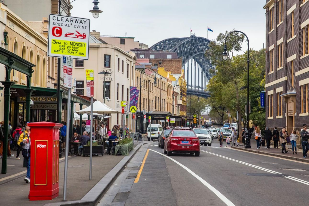 People walking through Sydney streets with shops, cafés, and local market activity.