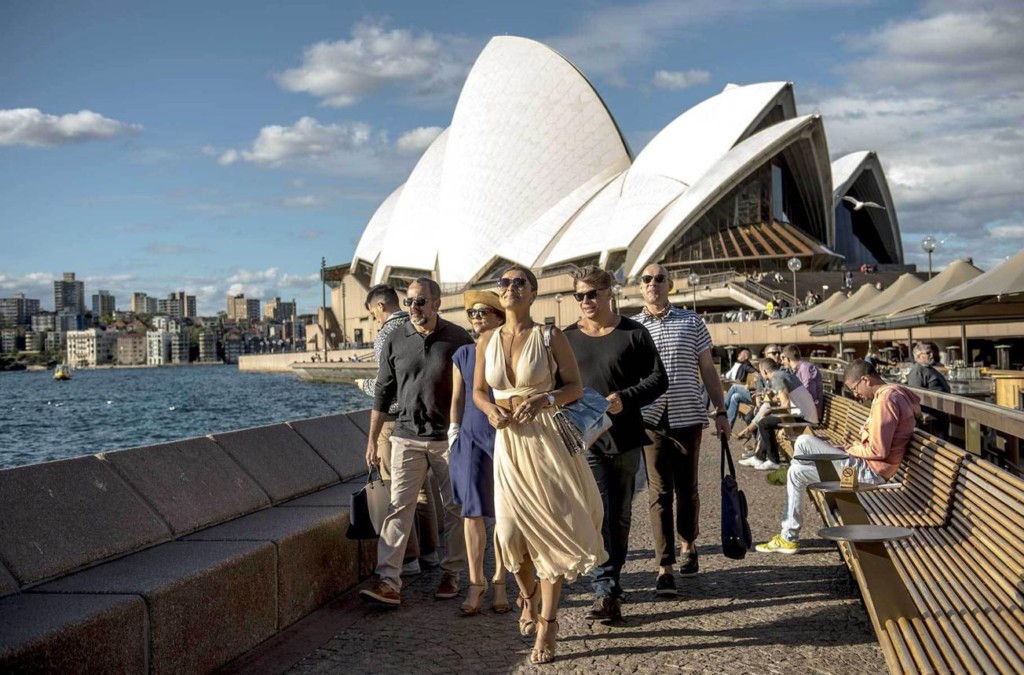 Tourists visiting the Royal Botanic Garden in Sydney with views of the Opera House and harbour.