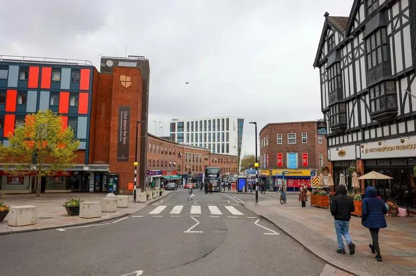 People walking through Coventry streets with shops, cafés, and local market activity.
