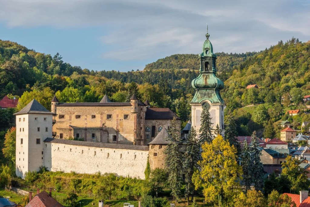 Tourists visiting the Old Castle in Banská Štiavnica with panoramic views of the town and surrounding hills.