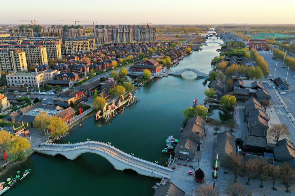 Tourists visiting a historic landmark in Tangshan with surrounding urban views.