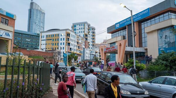 Visitors walking through streets in Kigali with local markets, shops, and pedestrian activity.