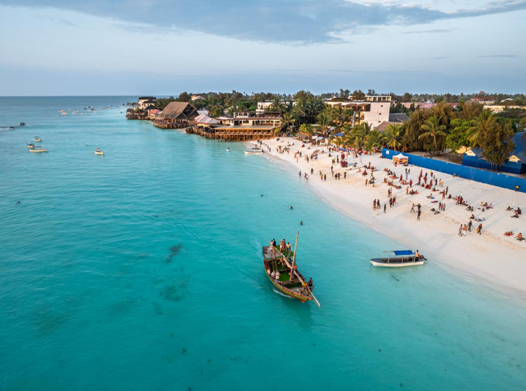 Visitors enjoying Nungwi Beach in Zanzibar, Tanzania, with sandy shores and clear blue waters.