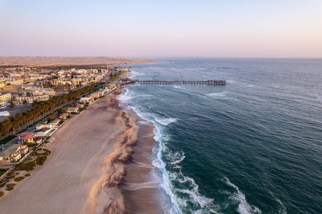 A panoramic aerial view of Swakopmund showing the coastal city, Atlantic Ocean shoreline, and surrounding Namib Desert landscape.