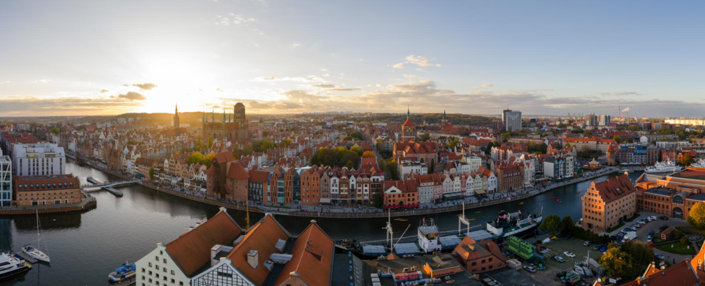 An aerial view of Gdańsk showing the city skyline along the Motława River and Baltic coast.