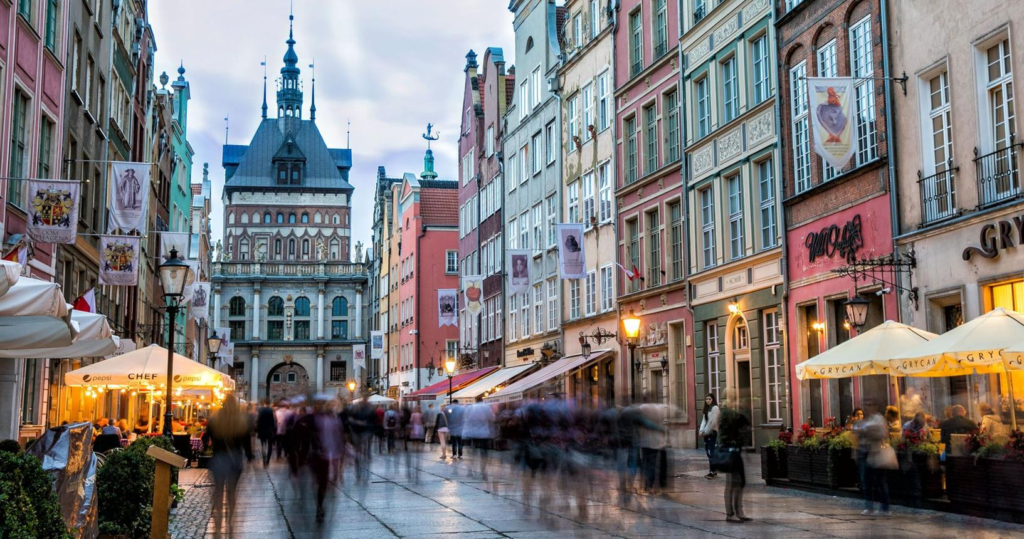People walking through Gdańsk streets with shops, cafés, and historic architecture.