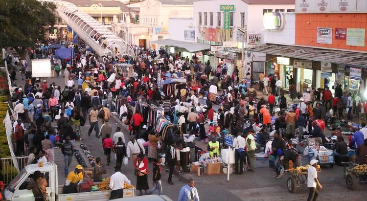 Visitors walking through streets in Harare with local shops, markets, and pedestrian activity.