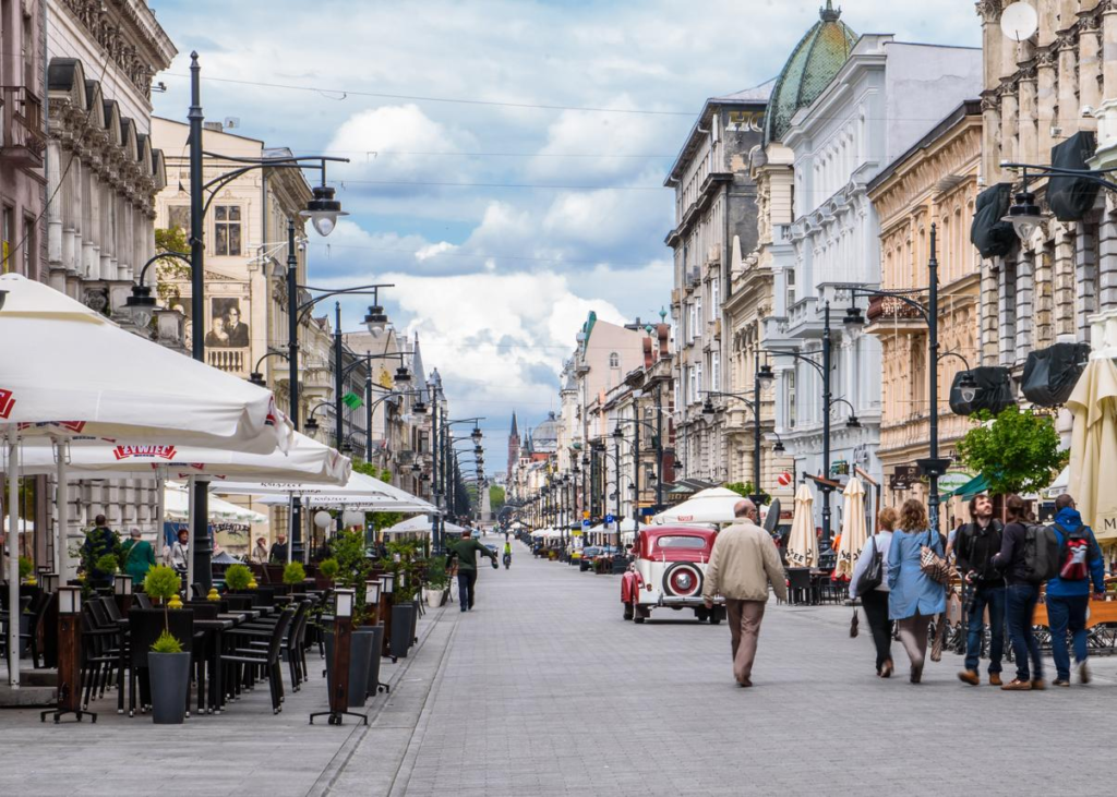 Tourists visiting Piotrkowska Street in Łódź with historic buildings and vibrant street life.