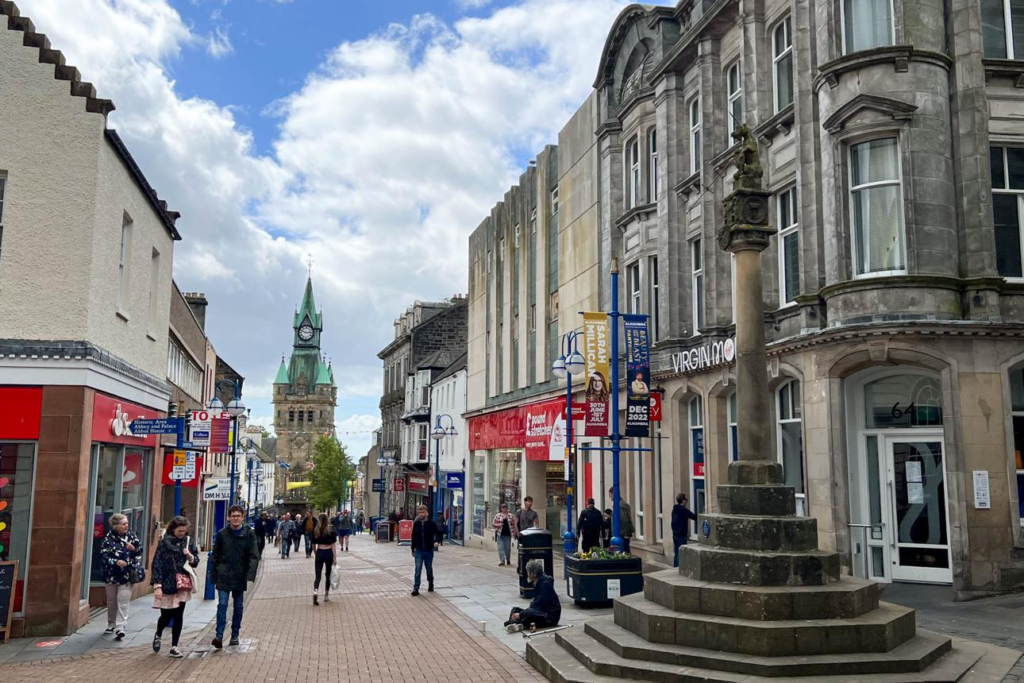 Visitors walking through streets in Dunfermline with local shops, cafés, and pedestrian activity.
