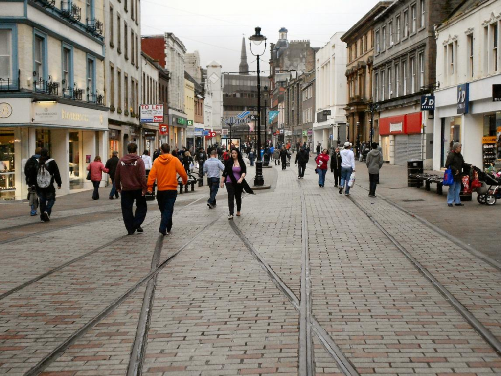 Visitors walking through streets in Dundee with local shops, cafés, and pedestrian activity.