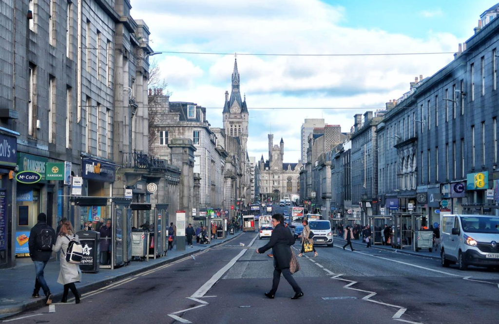 Visitors walking through streets in Aberdeen with local shops, cafés, and pedestrian activity.