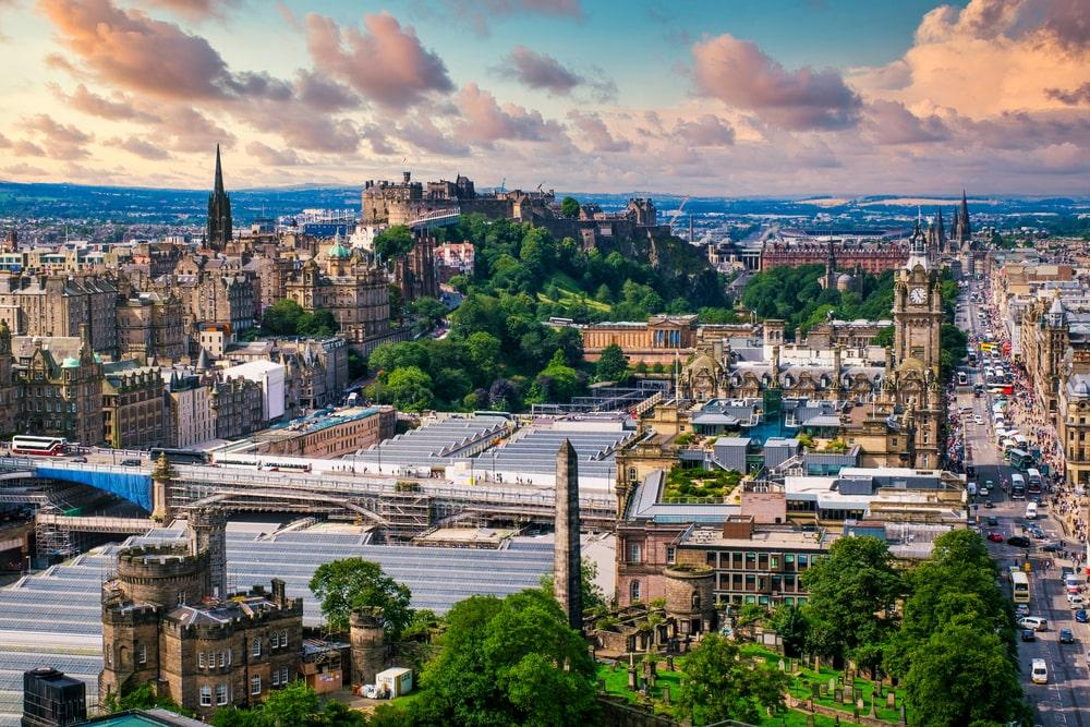 A panoramic aerial view of Edinburgh showing the cityscape, historic buildings, and Edinburgh Castle in Scotland, UK.