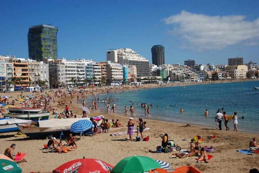 Visitors enjoying Las Canteras Beach in Las Palmas, Spain, with sand, water, and leisure activities.