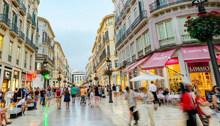 Visitors walking through streets in Málaga with shops, cafés, and pedestrian activity.