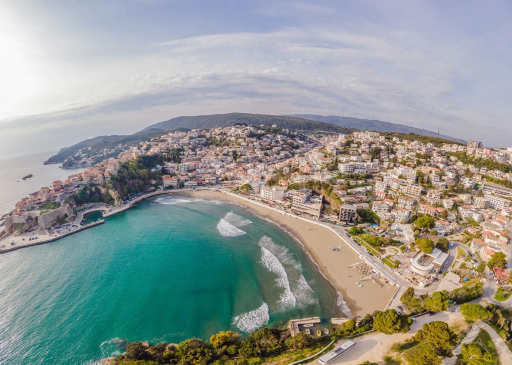 A panoramic aerial view of Ulcinj showing the town, coastline, and Adriatic Sea beaches in Montenegro.
