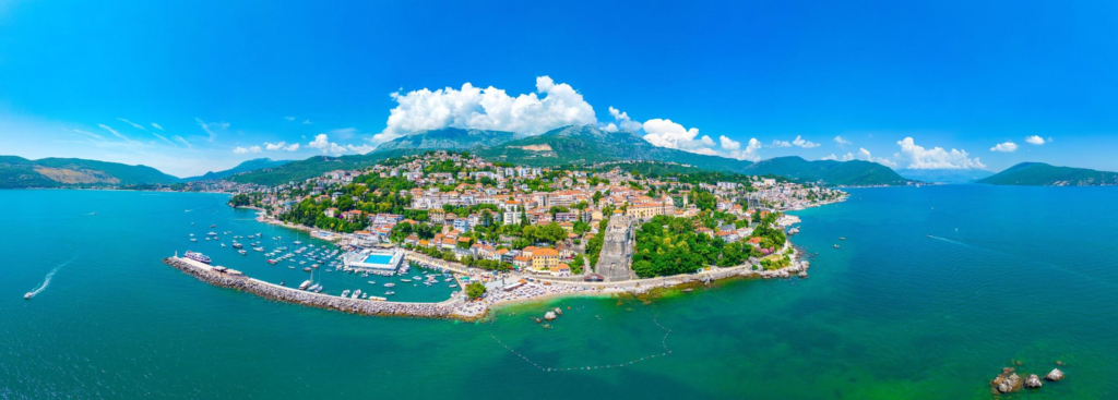 A panoramic aerial view of Herceg Novi showing the town, Adriatic coastline, and Bay of Kotor in Montenegro.