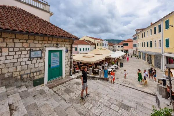 Visitors walking through streets in Herceg Novi with local shops, cafés, and pedestrian activity in the old town.