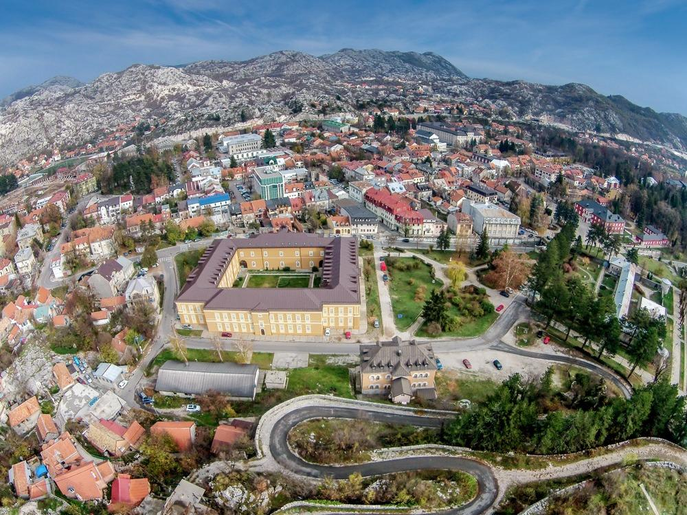 A panoramic aerial view of Cetinje showing the historic town, surrounding mountains, and cultural landmarks in Montenegro.