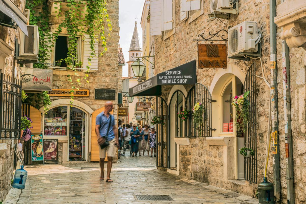 Visitors walking through streets in Budva’s old town with local shops, cafés, and pedestrian activity.
