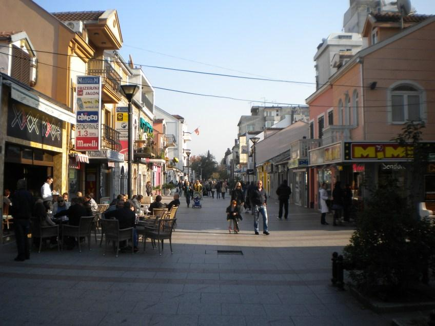 Visitors walking through streets in Podgorica with local shops, cafés, and pedestrian activity.