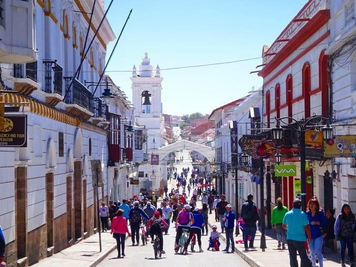 Visitors walking through streets in Sucre with local shops, cafés, and colonial-style architecture.