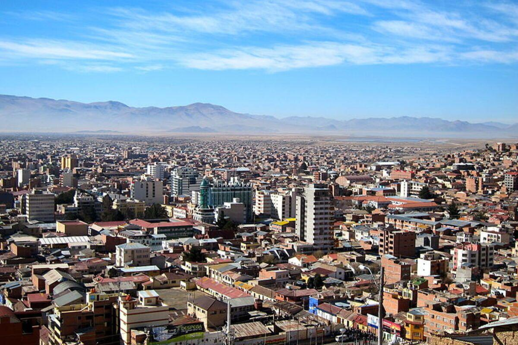 A panoramic aerial view of Oruro showing the cityscape and surrounding Andean mountains on the Altiplano in Bolivia.