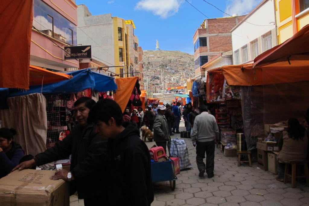 Visitors walking through streets in Oruro with local shops, cafés, and pedestrian activity.