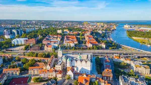 An aerial view of Szczecin showing the city skyline along the Oder River and port area.