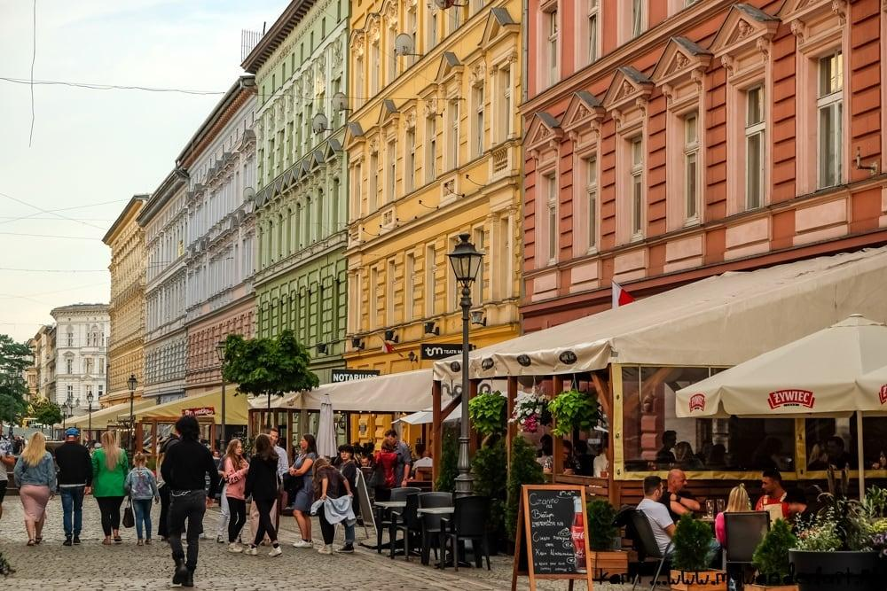 People walking through Szczecin streets with shops, cafés, and local market activity.