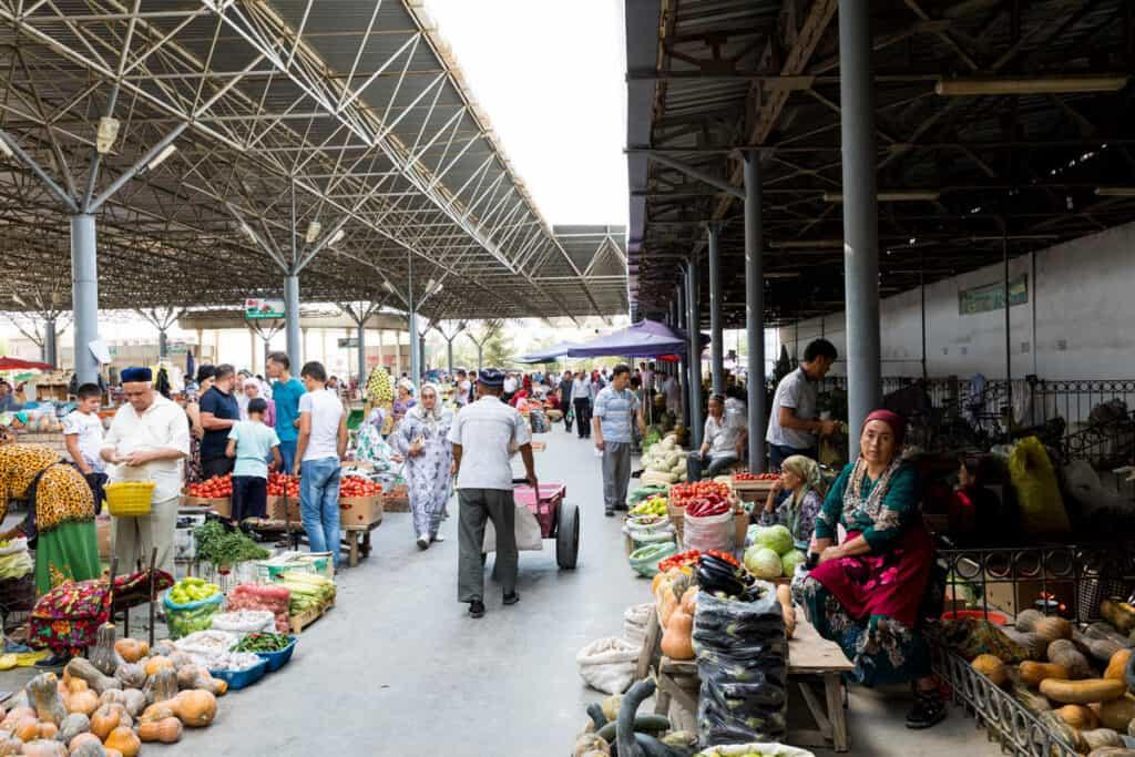 Visitors walking through streets in Fergana with local markets, shops, and pedestrian activity.
