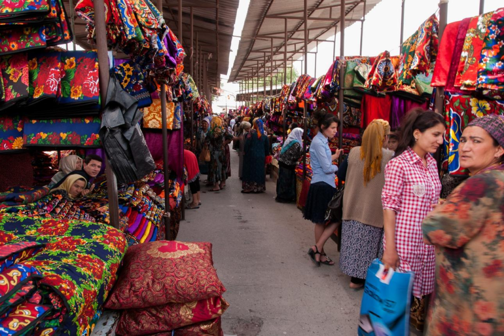 Visitors walking through streets in Margilan with local markets, shops, and pedestrian activity.
