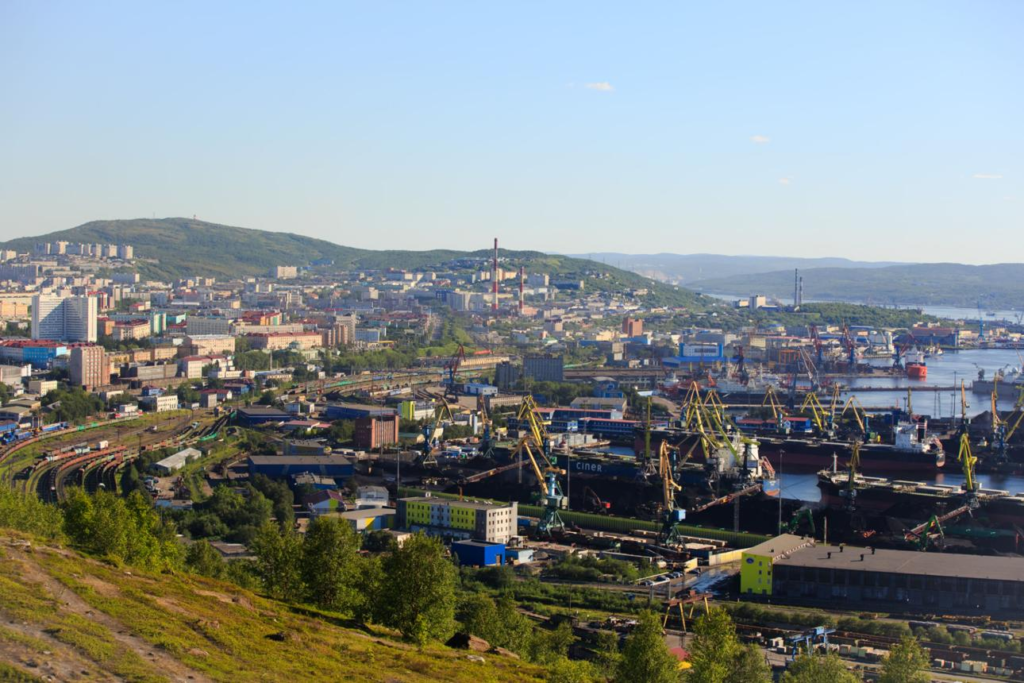 A panoramic aerial view of Murmansk showing the cityscape, port facilities, and Kola Bay in Russia.
