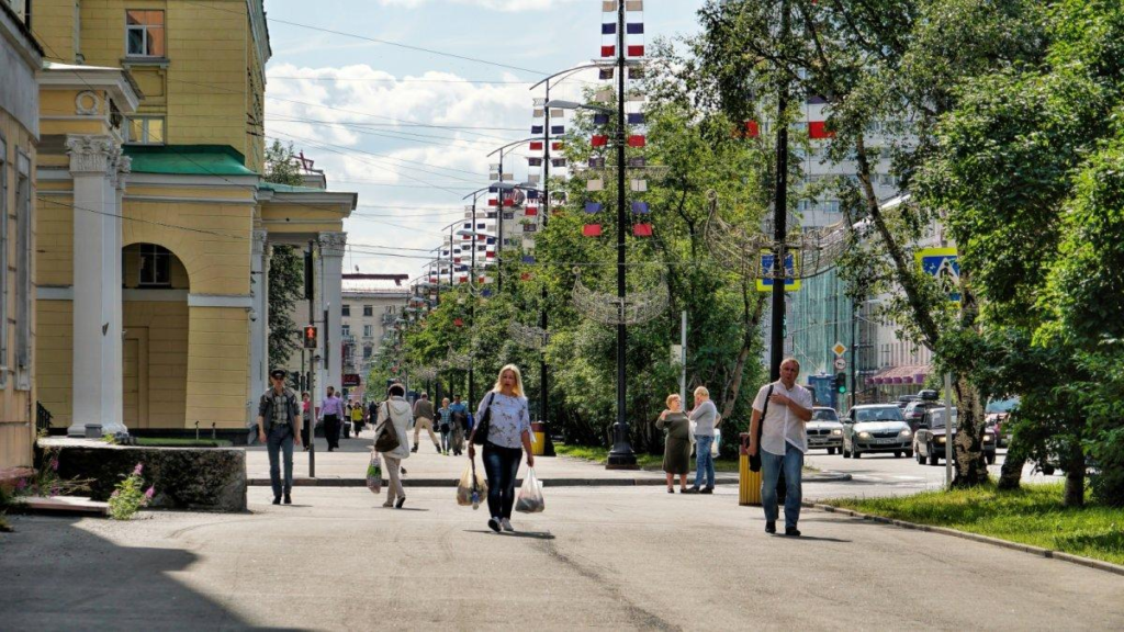 Visitors walking through streets in Murmansk with local shops, cafés, and pedestrian activity.