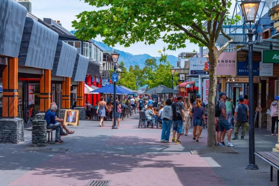 People walking through Queenstown streets with shops, cafés, and local activity.