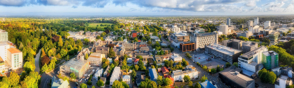 An aerial view of Christchurch showing the city skyline, Avon River, and surrounding Southern Alps.