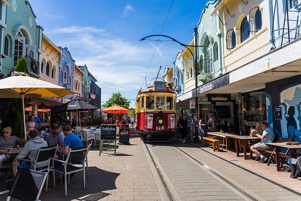 People walking through Christchurch streets with shops, cafés, and local market activity