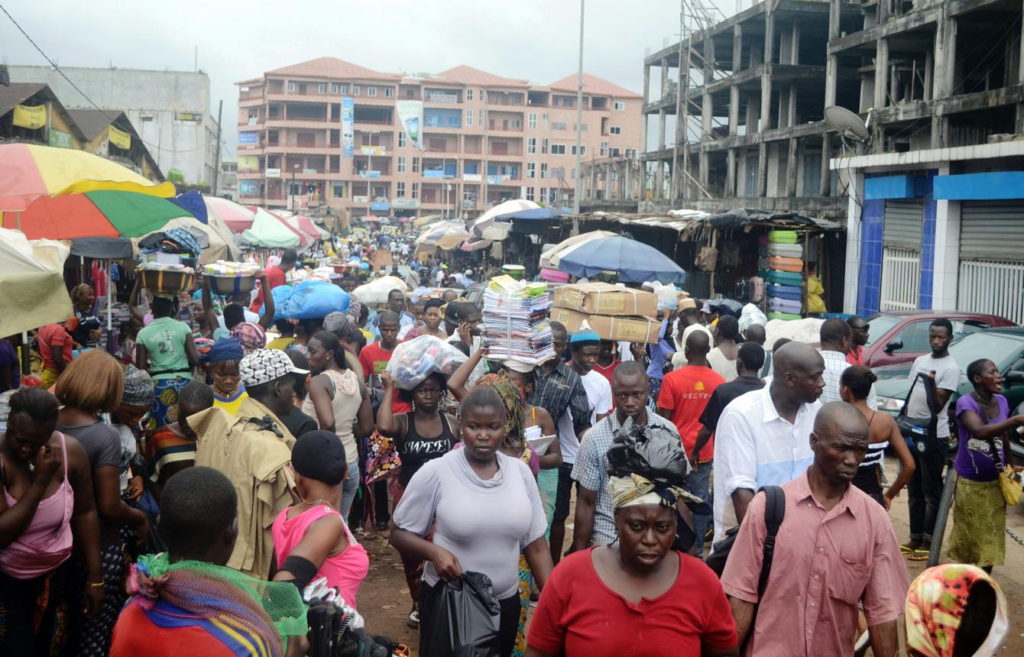 People walking through busy streets and markets in Conakry with shops and local vendors