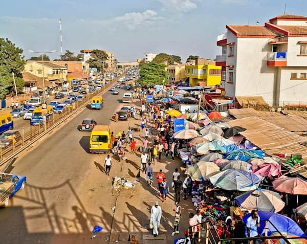 People walking through streets and markets in Bissau with shops and local vendors