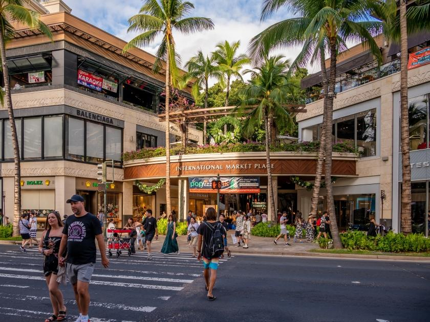 People walking through streets of Waikiki in Honolulu with shops, cafés, and local activity