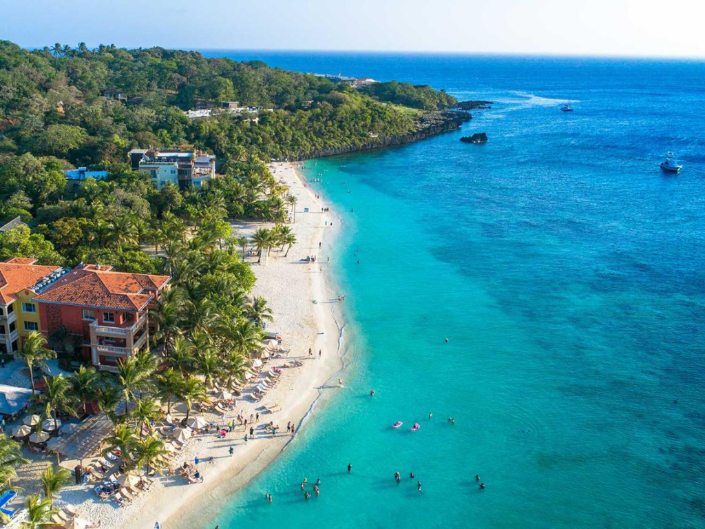 Tourists relaxing on sandy beaches with palm trees and turquoise waters on Roatán island, Honduras
