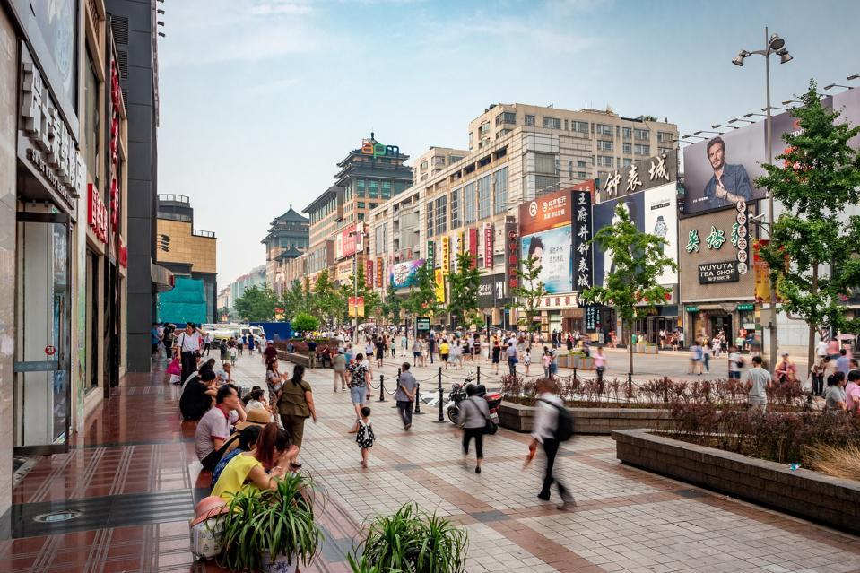 People walking along a lively pedestrian shopping street in central Beijing.
