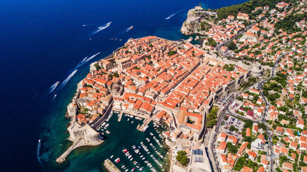 An aerial view of Dubrovnik's medieval Old Town surrounded by the Adriatic Sea and ancient stone walls.