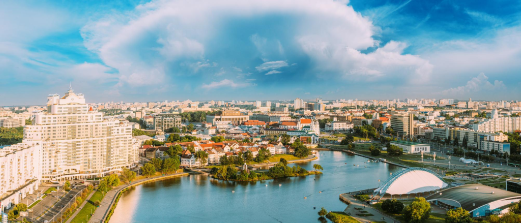A panoramic view of Minsk featuring modern buildings, parks, and the Svislach River.