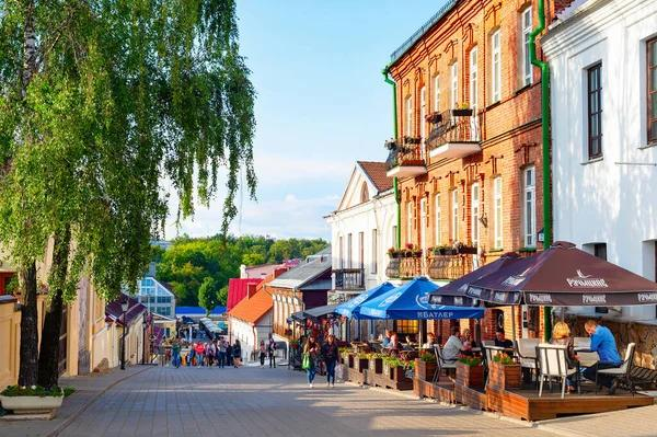 People walking through the historic Upper Town district with colorful buildings and outdoor cafés.