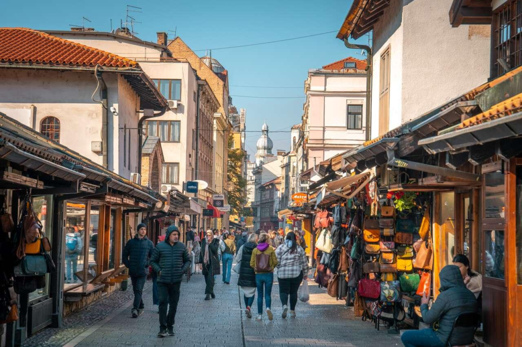 Visitors walking through the cobbled streets of Baščaršija lined with traditional shops and cafés.