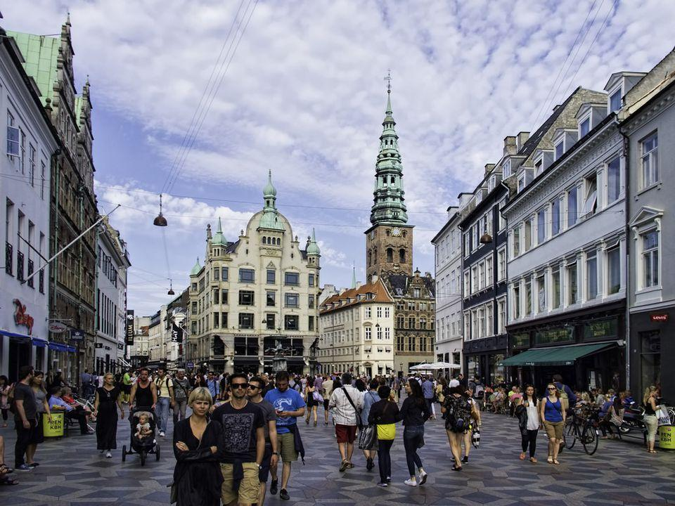 People strolling along Strøget, a lively pedestrian shopping street lined with historic buildings and cafés.