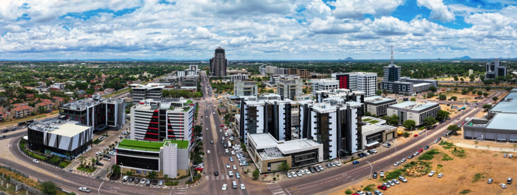 A panoramic view of Gaborone with modern buildings, green spaces, and surrounding hills.