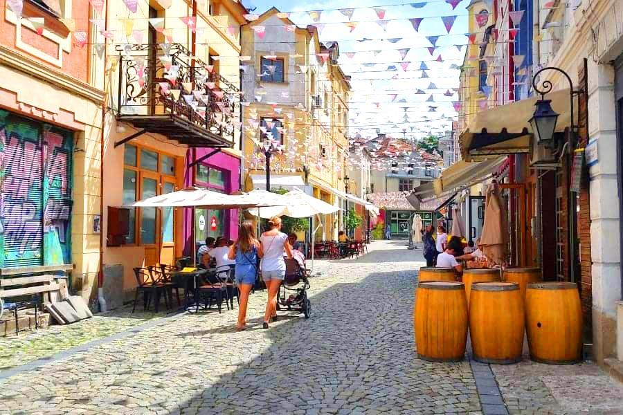 Visitors walking along cobblestone streets lined with colorful historic houses in Plovdiv's Old Town.
