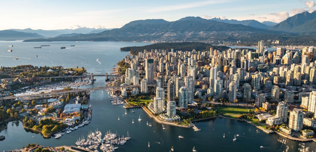 A panoramic view of Vancouver with its skyline, harbor, and snow-capped mountains in the background.